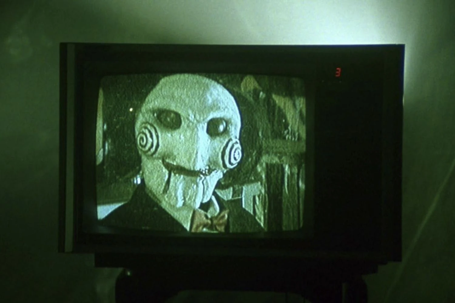 Saw: Billy, the trap-maker's puppet, on the screen of an old TV.